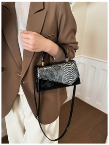 Close-up of stylish contrast color crossbody bag with snake skin pattern and top handle