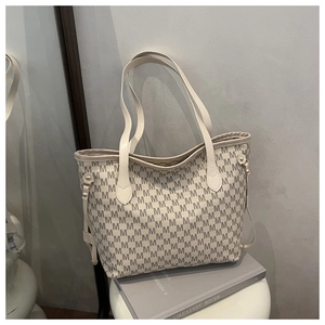 Detail of beige tote bag featuring all-over M letter print and slender shoulder straps