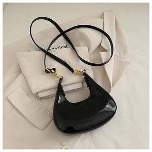 Détail du sac demi-lune en cuir verni brillant noir avec boucle dorée et fermeture éclair