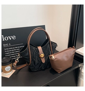 Detail of black pleated bucket bag with brown contrast trim and amber texture buckle