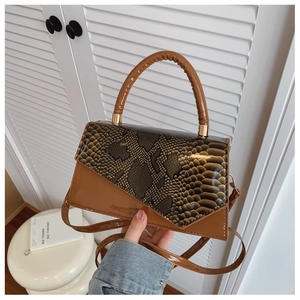 Detail of a brown patchwork handbag with snakeskin texture and golden metal hardware