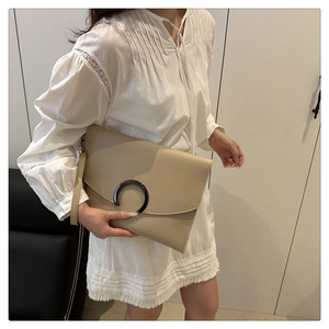 Close-up of beige envelope clutch with matte leather and semi-circle ring buckle decoration