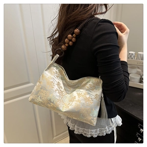 Detail of traditional landscape embroidery and wooden bead strap on shoulder bag