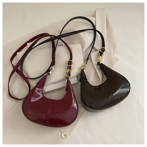 Détail de sacs demi-lune en cuir verni brillant bordeaux et marron avec boucles dorées