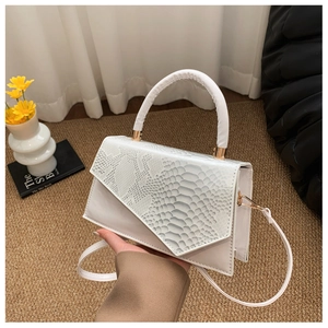 Detail of snakeskin embossed flap and gold metal clasp on beige crossbody handbag