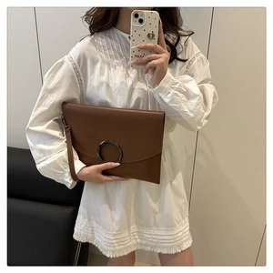 Brown leather envelope clutch with a large metal ring buckle and wrist strap