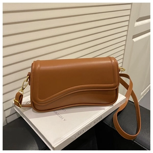 Detail view of the caramel brown crossbody bag with unique wave design and gold hardware