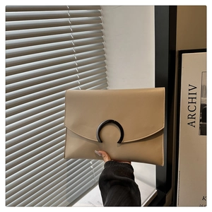 Detail of beige leather envelope clutch bag with black half-moon metal handle and clasp