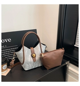 Detail view of silver pleated tote bag with brown leather strap and inner pouch