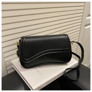 Close-up of black matte leather saddle bag featuring gold metal hardware and rounded flap