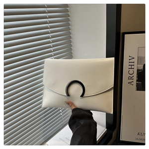 Detailed view of a cream leather envelope clutch bag with black metallic C-ring clasp
