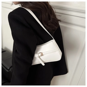 Detail of white minimalist underarm bag with gold buckle on a black wool coat
