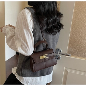 Detail showing deep brown lychee grain texture bag with golden clasp worn on shoulder