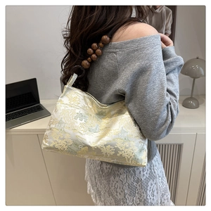Detail of vintage jacquard underarm bag with golden landscape pattern and wooden beads