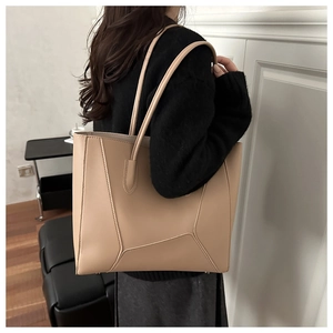 Detail view of khaki leather tote bag with geometric stitching on model's shoulder