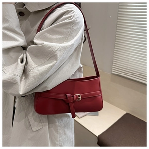 Detail view of retro red leather shoulder bag with decorative metal buckle and strap