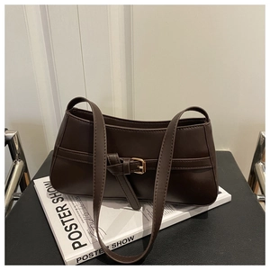 Detailed view of deep brown vintage underarm bag with decorative belt buckle on a magazine