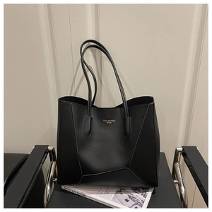 Detail of black leather tote bag featuring geometric stitching and brand logo on a chair