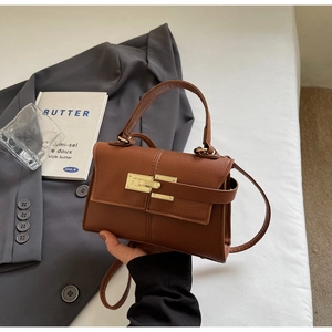 Detail of brown litchi pattern leather bag with golden clasp and top handle