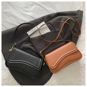 Flat lay of wave-flap crossbody bags in black and brown with fine gold hardware
