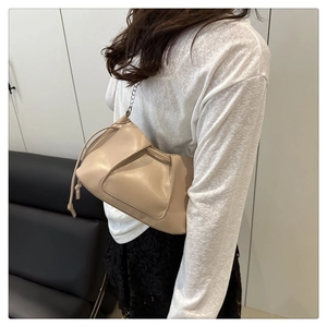 Détail du sac à bandoulière plissé beige avec cordon et chaîne en argent élégante