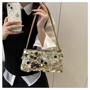 Detail of shimmering sequin texture on a stylish gold crossbody bag held by a model