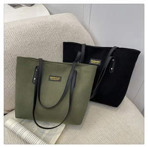 Detail of corduroy tote bags in olive green and black with faux leather handles