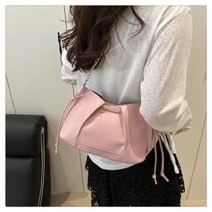 Gros plan d'un sac à bandoulière rose plissé avec chaîne argentée et cordons en cuir