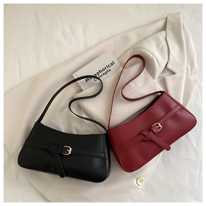 Close-up of black and burgundy underarm bags with smooth PU leather and gold buckle