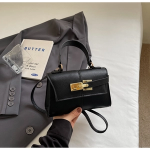 Detail of black lychee grain leather mini handbag with gold metal clasp closure