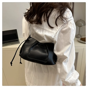 Sac à bandoulière plissé noir chic avec chaîne argentée porté par un mannequin en intérieur