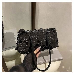 Detailed view of shimmering black sequins on a stylish underarm bag with thin shoulder strap