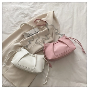 Détails des sacs à bandoulière plissés blanc et rose avec chaînes sur un tissu blanc