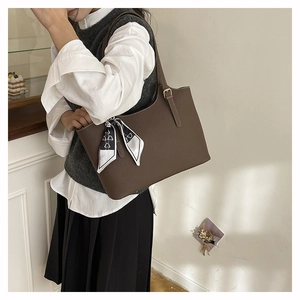 Brown lychee leather tote bag with silk scarf detail shown in a stylish home setting