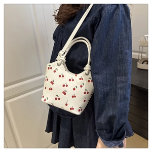 Close-up of cherry print bucket bag showing high-capacity design and sleek shoulder strap