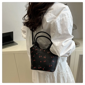 Fashionable cherry print bucket bag showing model side view and adjustable strap detail