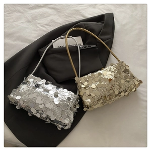 Detail view of shimmering silver and gold sequin shoulder bags on a dark blazer suit