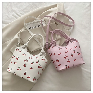 Detail of cherry print tote bags in white and pink with knotted handles on a suit jacket