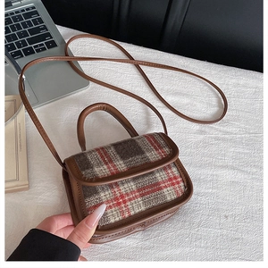 Détail d'un mini sac vintage en tweed à carreaux rouges avec poignée en cuir brun