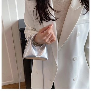 Close-up of a silver metallic mini handbag with thin shoulder strap and side lettering