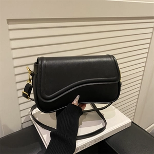 Chic black wave flap crossbody bag with gold hardware on a minimalist background