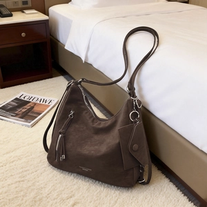 Coffee brown suede-textured tote bag with silver zippers on a white fluffy carpet