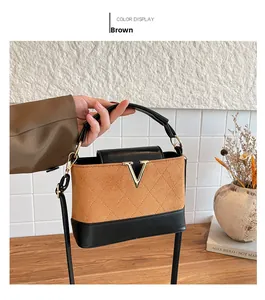 Detail of brown suede crossbody bag with diamond stitching and golden V metal hardware