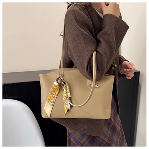 Close-up of khaki tote bag featuring an elegant printed silk scarf on the handle