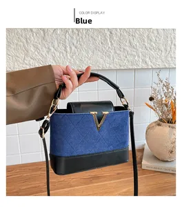 Detail of blue suede and black leather bag with gold V-shaped logo and quilted pattern