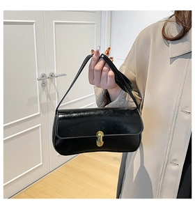 Detail of a chic black glossy shoulder bag featuring a stylish gold metal lock and leather strap