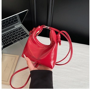 Detail of red patent leather handbag with black lettering and knotted strap design