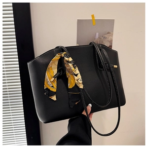 Detail of black matte leather tote bag featuring a decorative printed silk scarf on handle