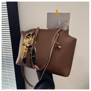 Detail of dark brown tote bag with decorative silk scarf and white stitching accents