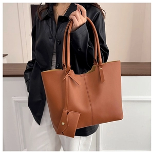 Detail of the brown PU leather tote bag showing fine texture and a small hanging pouch